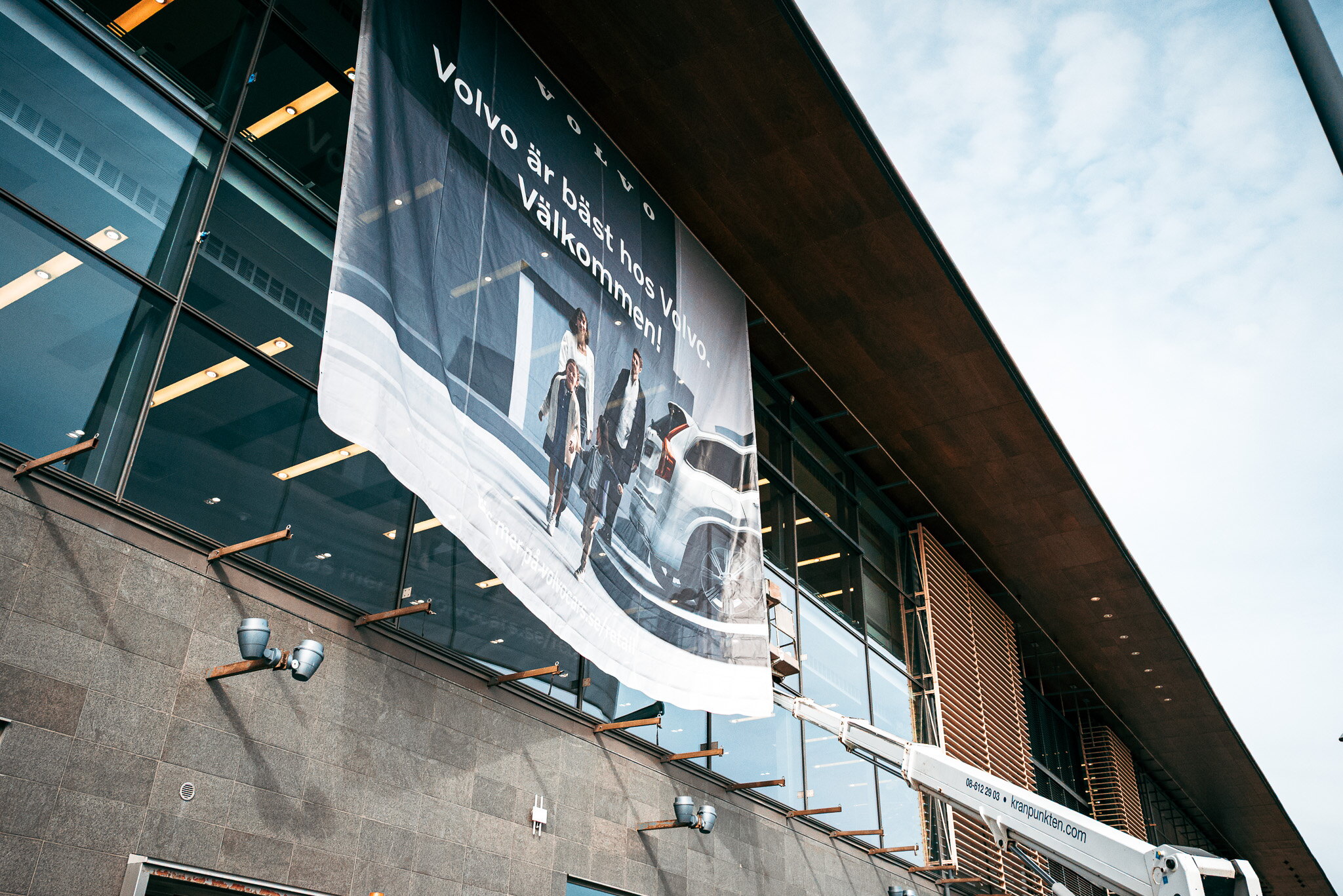 Stor Volvo-vepa monteras högt på en glasfasad med hjälp av skylift