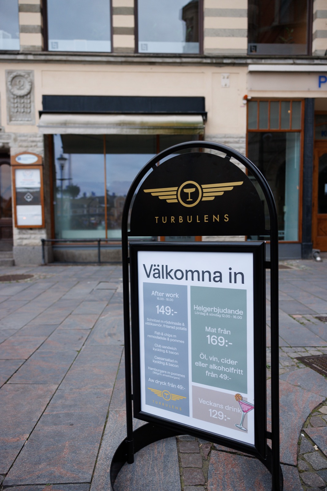 Gatupratare med Turbulens logotyp och meny på trottoaren framför restaurangen