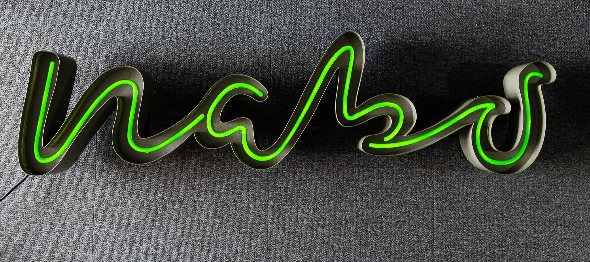 Skylt i skrivstil med grön LED-neonslang i lackerad kanal