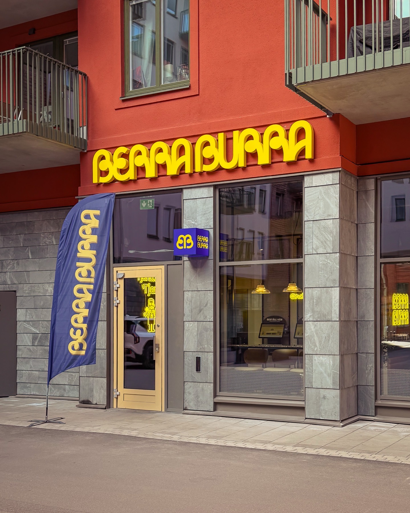 Restaurangfasad med gula profilbokstäver, ljuslåda och beachflagga