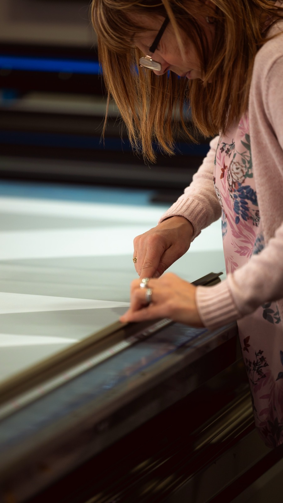Medarbetare justerar material vid den stora printmaskinen i produktionen