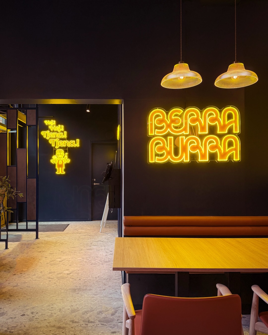 Gula belysta Berra Burra-logotyper på en mörk vägg i restaurangen