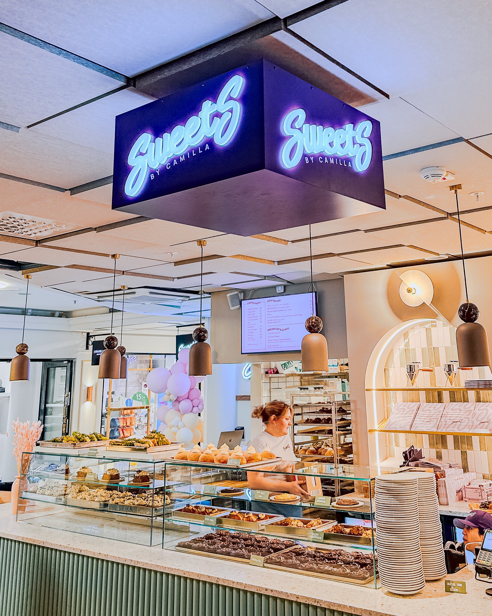 Belyst dubbelsidig takskylt med Sweet's-logotyp ovanför disken