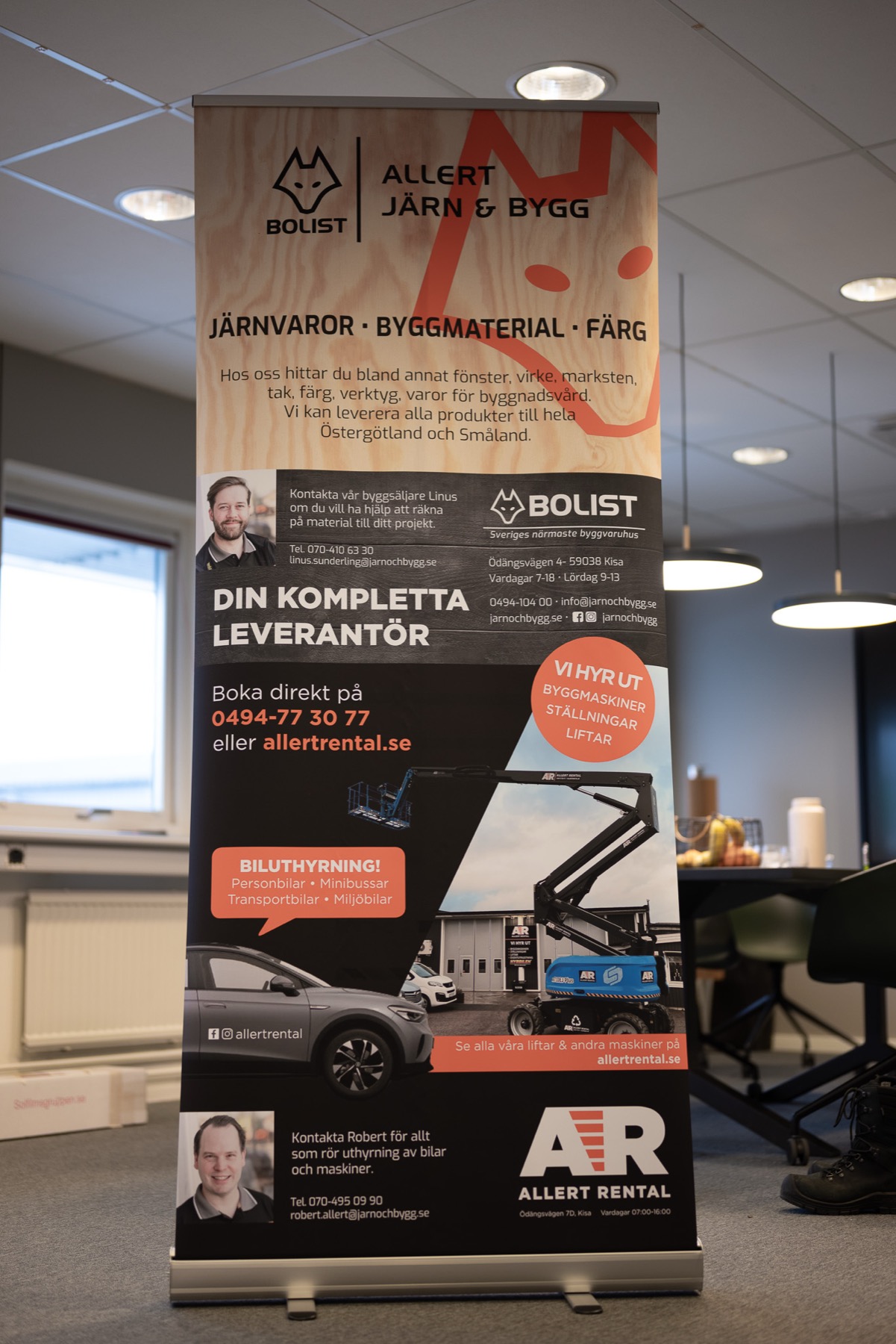 Rollup för Bolist och Allert Järn och Bygg uppställd i kontorsmiljö, med kontaktpersoner, tjänster och telefonnummer på våden