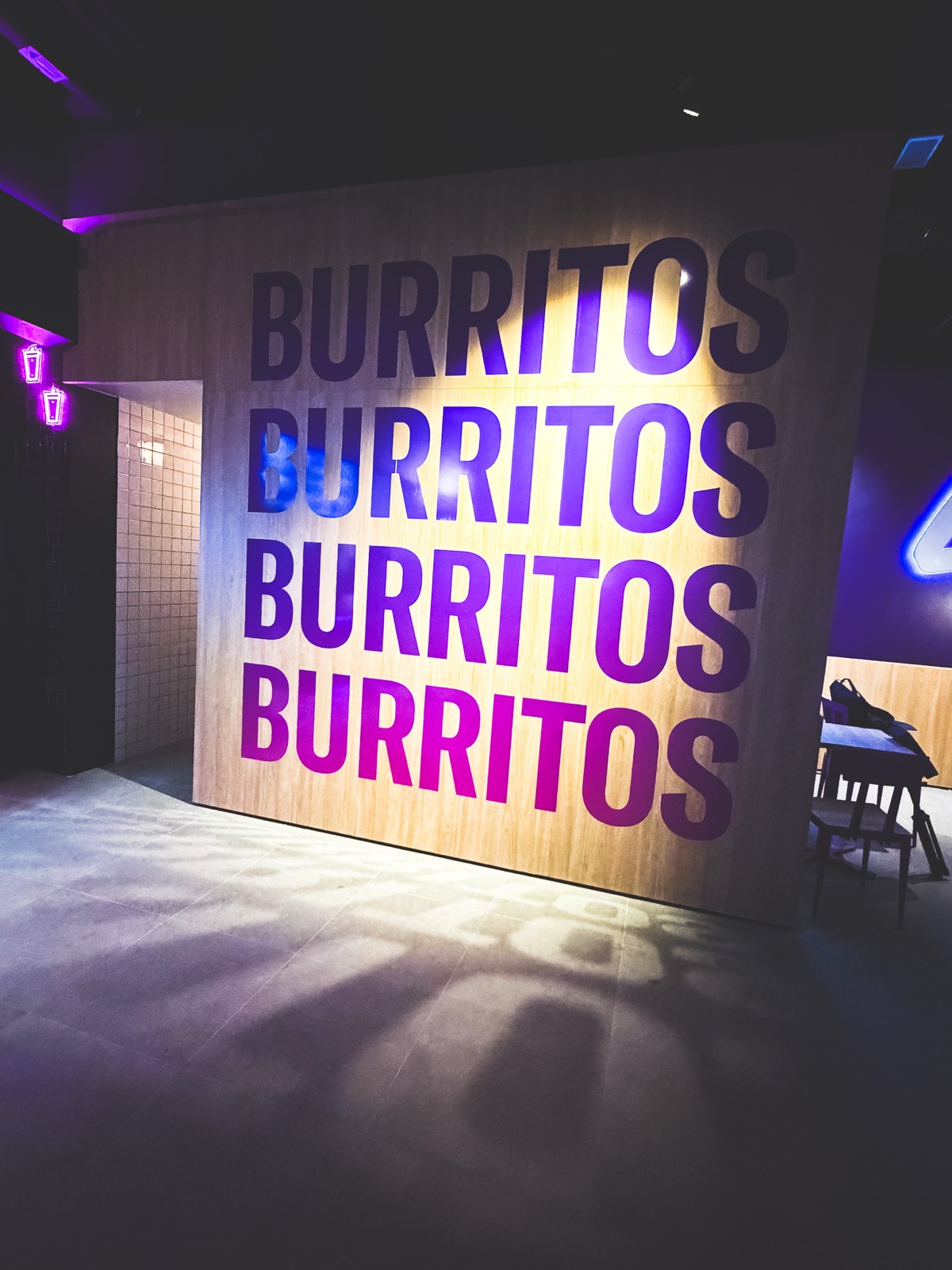 Väggpanel med ordet BURRITOS folietryckt fyra gånger i lila och rosa toner